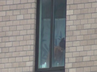 the girl takes a shower by the windowaa a, and she is being filmed)